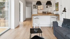 Een moderne keuken met een centraal eiland, twee barkrukken, een eettafel met stoelen en een bank.