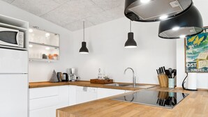 Een moderne keuken met witte kasten, een houten eiland, roestvrijstalen apparatuur en hanglampen.