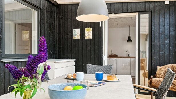 Een moderne keuken met donkere houten wanden, een groot raam en een eethoek met een tafel voor twee.