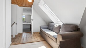 Un dormitorio tipo loft con techo inclinado, un banco empotrado y un tragaluz.