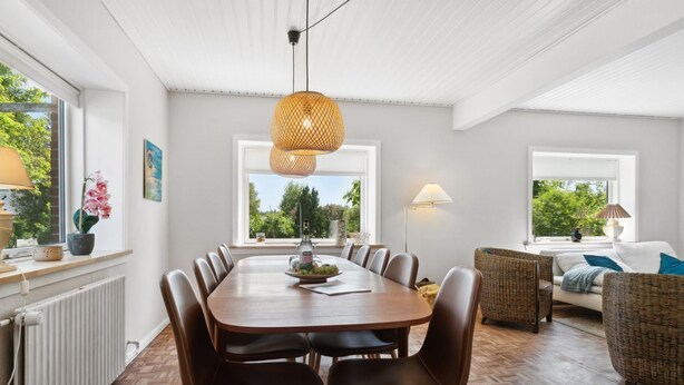 Un comedor con una mesa de madera, sillas de cuero y una lámpara colgante de fibras.