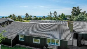 Un bâtiment moderne avec un toit en métal, de grandes fenêtres et une cour verdoyante.