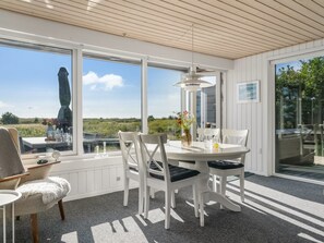 Un espace repas avec une table ronde, des chaises blanches et une vue sur l’extérieur.