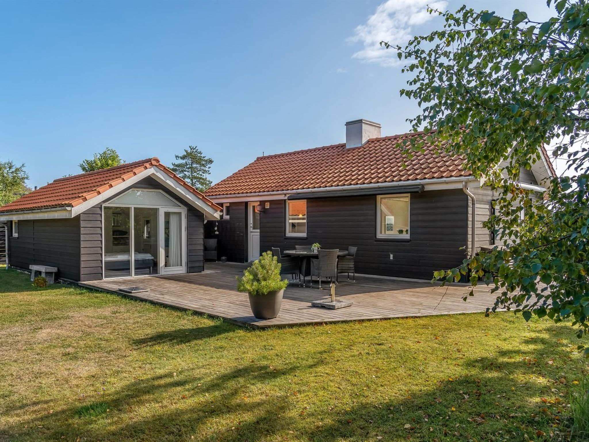 A modern house with a patio, a small garden, and a dining area.