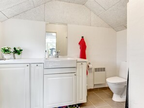 A bathroom with a white vanity, a mirror, a red towel, a toilet, and a window. - "Mumme" - 100m from the sea by Interhome (Hals)