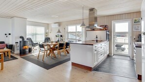 Una cucina moderna con isola centrale, pavimento in legno e soffitto alto con travi a vista.