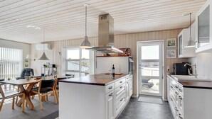 Una cucina moderna con mobili bianchi, un'isola centrale e un'area pranzo con tavolo e sedie in legno.