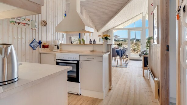 Une cuisine moderne dotée d’un îlot central, d’un coin repas offrant une vue agréable et d’un plafond en bois.