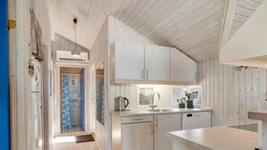Une cuisine moderne avec des meubles blancs, un lave-vaisselle encastré et une fenêtre qui laisse entrer la lumière naturelle.