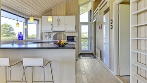 Une cuisine moderne dotée d’un grand îlot central, de tabourets de bar et de luminaires suspendus.