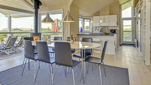 Une cuisine moderne avec des meubles blancs, un îlot central et des luminaires suspendus.