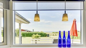 Une cuisine dotée d’une grande fenêtre donnant sur un jardin et offrant une vue sur la mer.