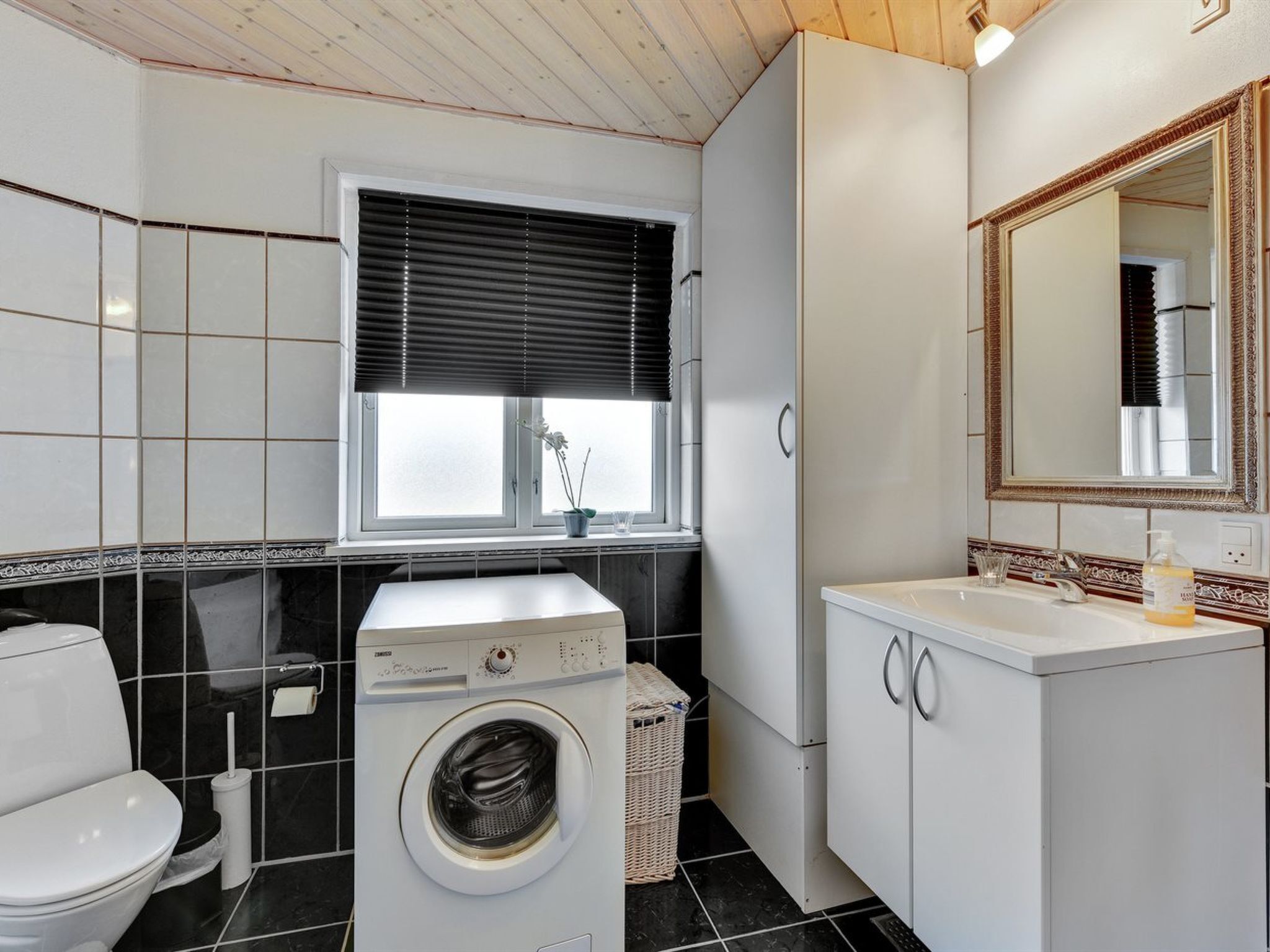 A compact, modern bathroom with a washing machine, toilet, and sink.
