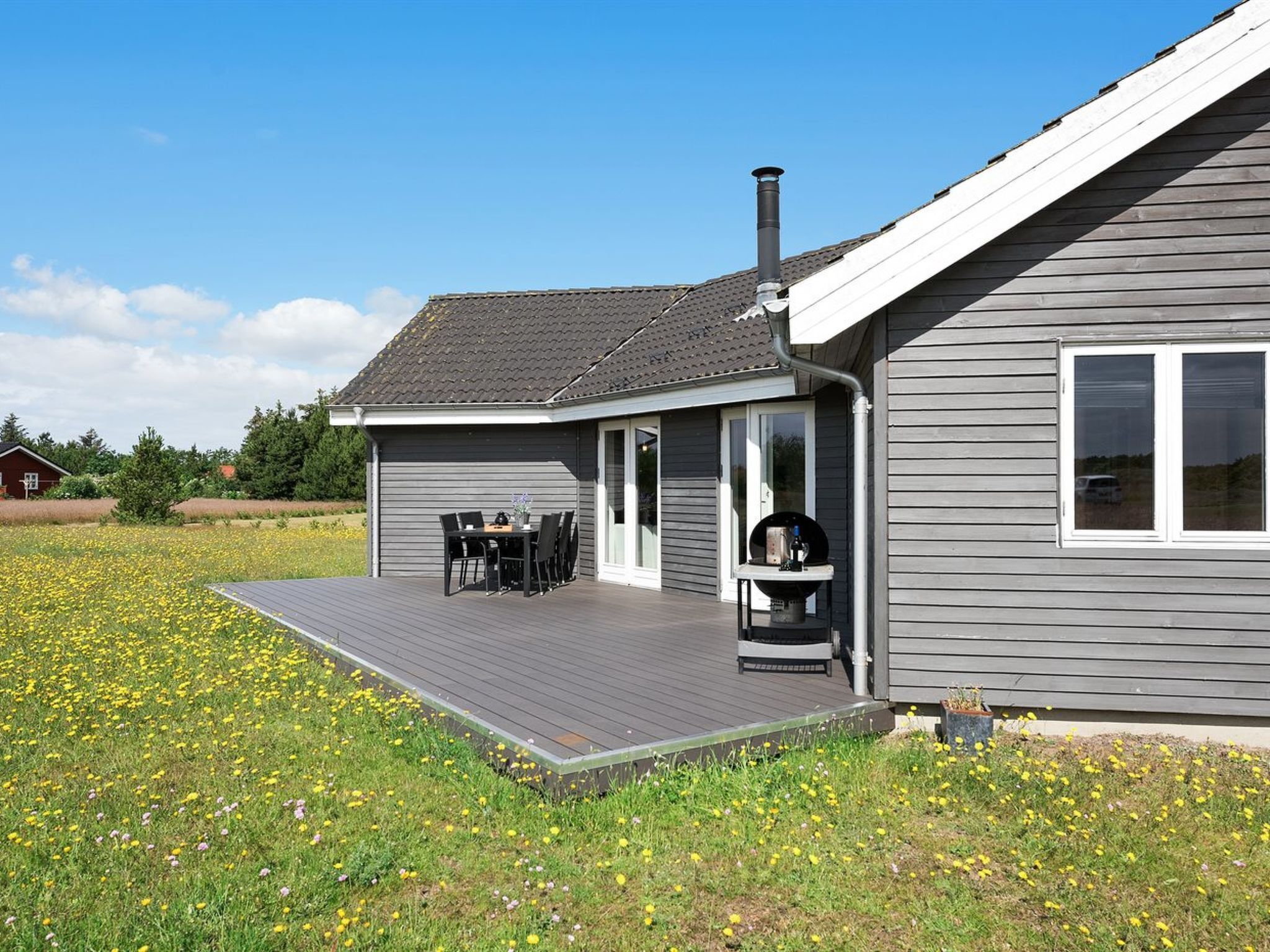 A modern house with a covered patio, a barbecue grill, and a large deck.