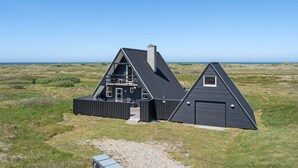 Een modern huis met een ruim terras, een garage en uitzicht op zee.