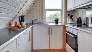 Een kleine keuken met witte kasten, een zwart aanrechtblad en een raam dat voor natuurlijk licht zorgt.