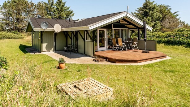 Une maison de plain-pied dotée d’un patio couvert, d’une antenne parabolique et d’un petit jardin.