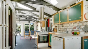 Une cuisine moderne avec des armoires blanches, un four encastré et un grand îlot central doté d’un évier.