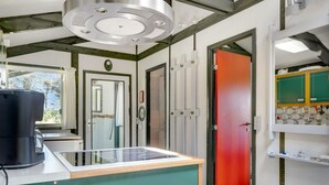 Une cuisine au design moderne, dotée d’un îlot central, d’un évier et d’une porte rouge donnant sur une autre pièce.