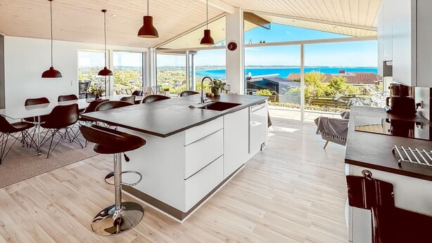 Una cocina moderna con una isla grande, taburetes de bar y vista al océano.