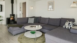 Una sala moderna con un sofá modular, una mesa de centro redonda, una chimenea y una obra de arte enmarcada en la pared.