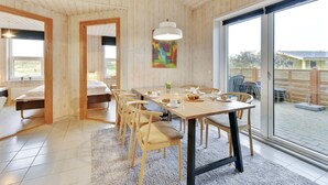 Un comedor moderno con una mesa de madera, sillas y un gran ventanal con vistas al exterior.