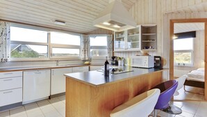 Una cocina moderna con una isla central, muebles blancos y vistas al exterior.