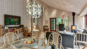 A cozy living room with a television, wicker furniture, a glass table with fruit, and a wood-paneled interior.