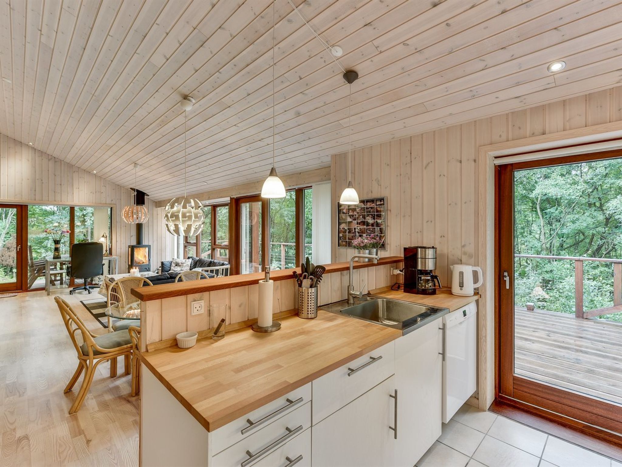 A modern kitchen with wooden cabinets, a central island, and a large window overlooking greenery.