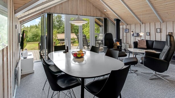 Een moderne, open woonkamer met een grote eettafel, comfortabele zithoek en een open haard.
