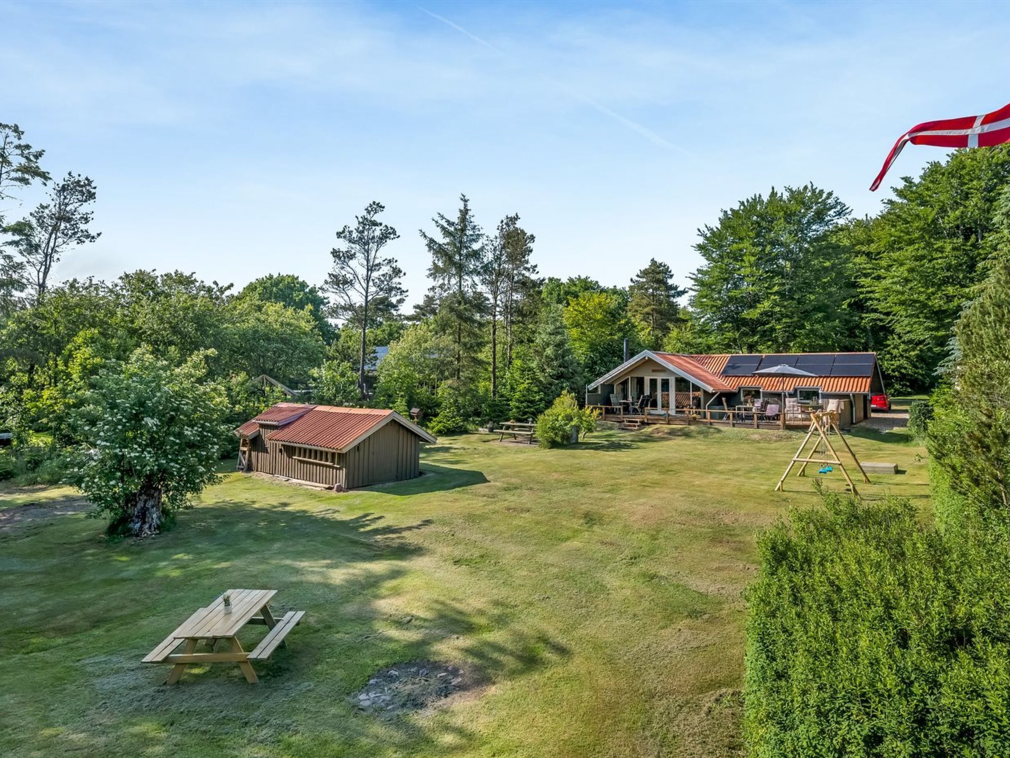 A rustic cabin with a metal roof, surrounded by a lush green landscape and tall trees.