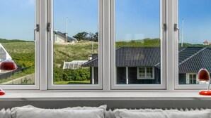 Quarto com uma janela ampla que dá para uma área gramada e edifícios.