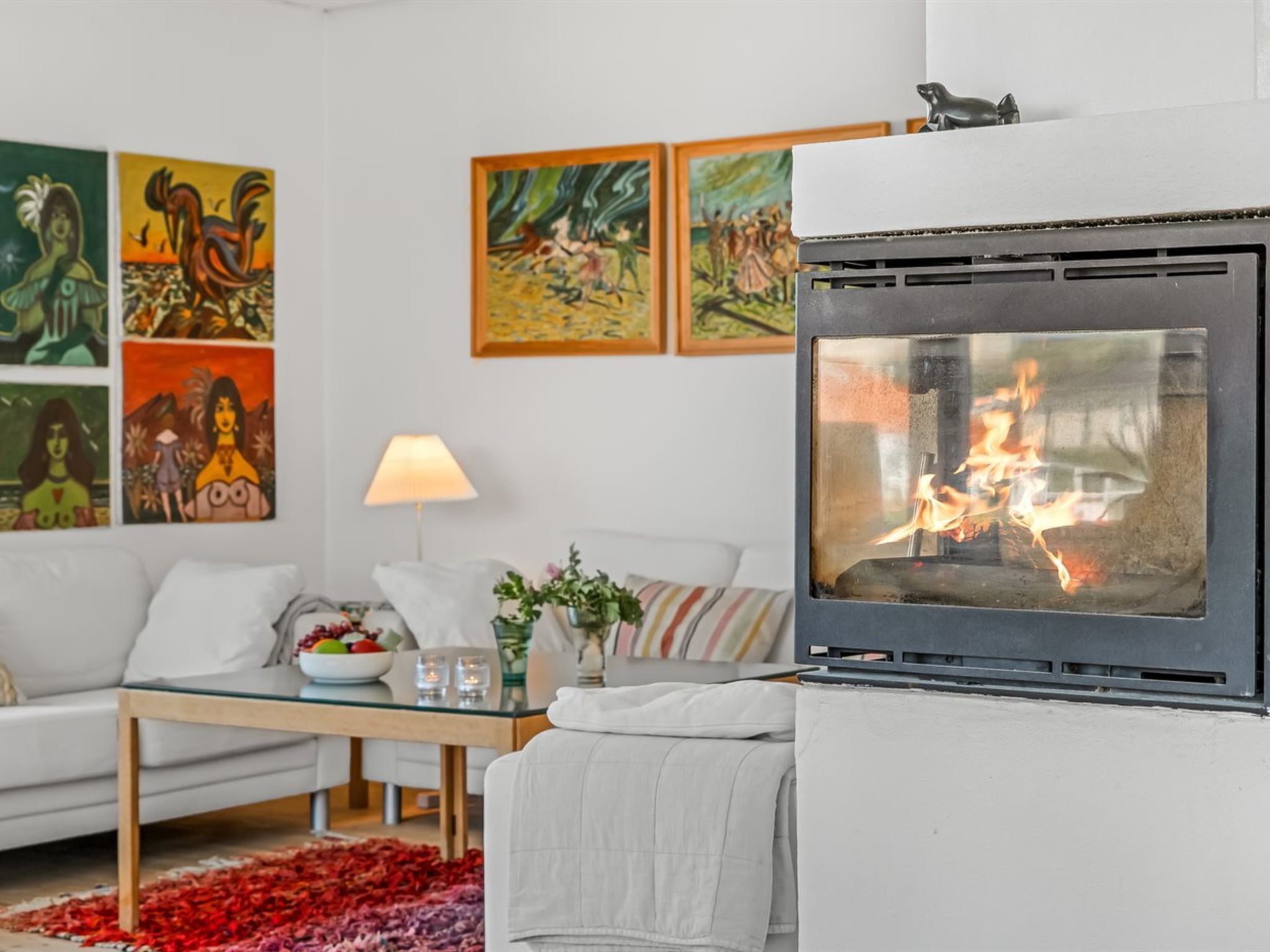 A modern living room with a fireplace, a sofa, a coffee table, and artwork on the walls.