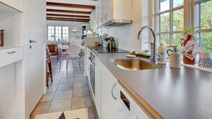 A modern kitchen with a central island, stainless steel appliances, and a large window providing natural light. - "Tordis" - 250m to the fjord by Interhome (Roslev)