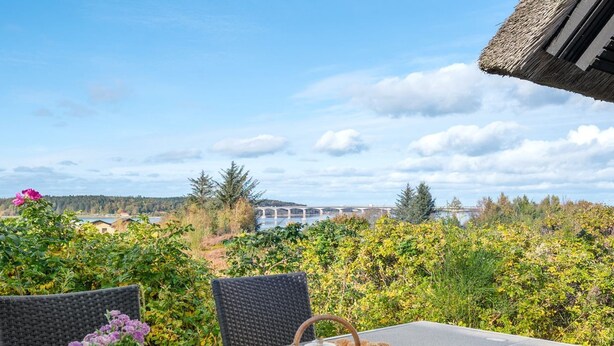 A table set outdoors with a view of a bridge and forest. - "Tordis" - 250m to the fjord by Interhome (Roslev)