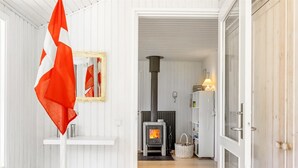 A cozy room with a white wooden interior, a fireplace, and a flag hanging on the wall. - "Gullborg" - 800m from the sea by Interhome (Løkken)