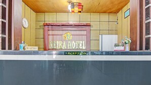 A reception desk with a sign reading "NEIRA HOTEL" and a clock above it.