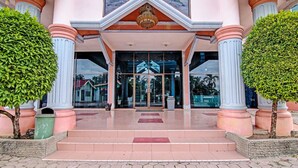 A building entrance with a grand staircase, large glass doors, and symmetrical columns.
