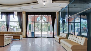 A spacious lobby with a high ceiling, large windows, and two sofas.