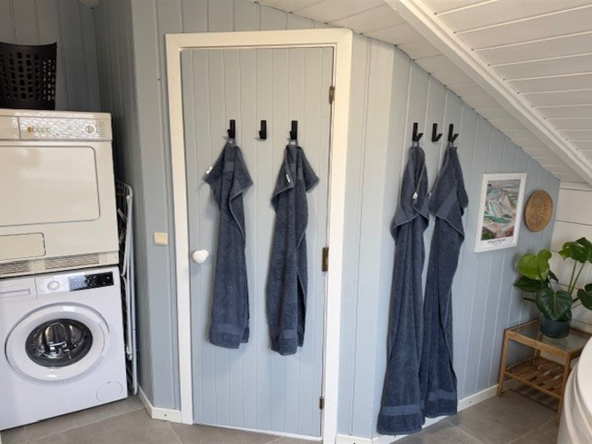 A laundry area with a washing machine and a drying rack against a door.