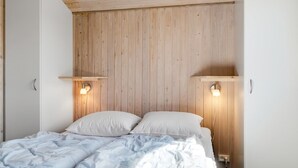 Une chambre à coucher avec un lit, une tête de lit en bois, des lampes de chevet et une armoire blanche.