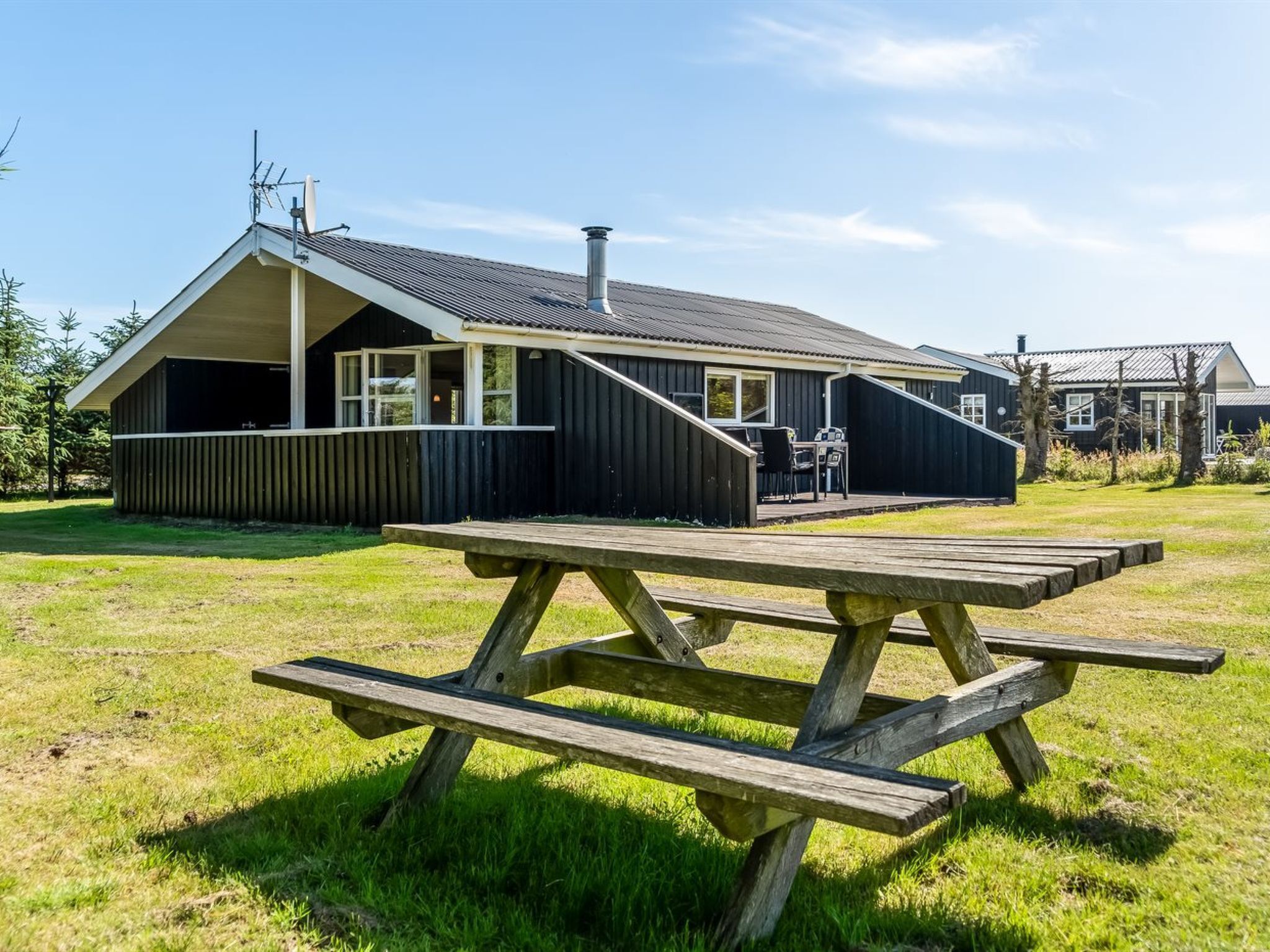 A wooden picnic table in a grassy area with a building in the background.