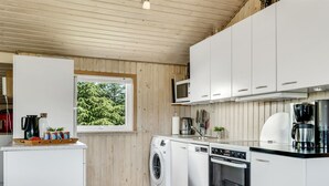 Une cuisine compacte équipée d’un lave-linge, d’un lave-vaisselle, d’un four à micro-ondes et d’une machine à café.