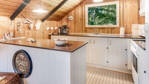 Una cocina moderna con paredes de madera, un ventanal grande y piso de baldosas.