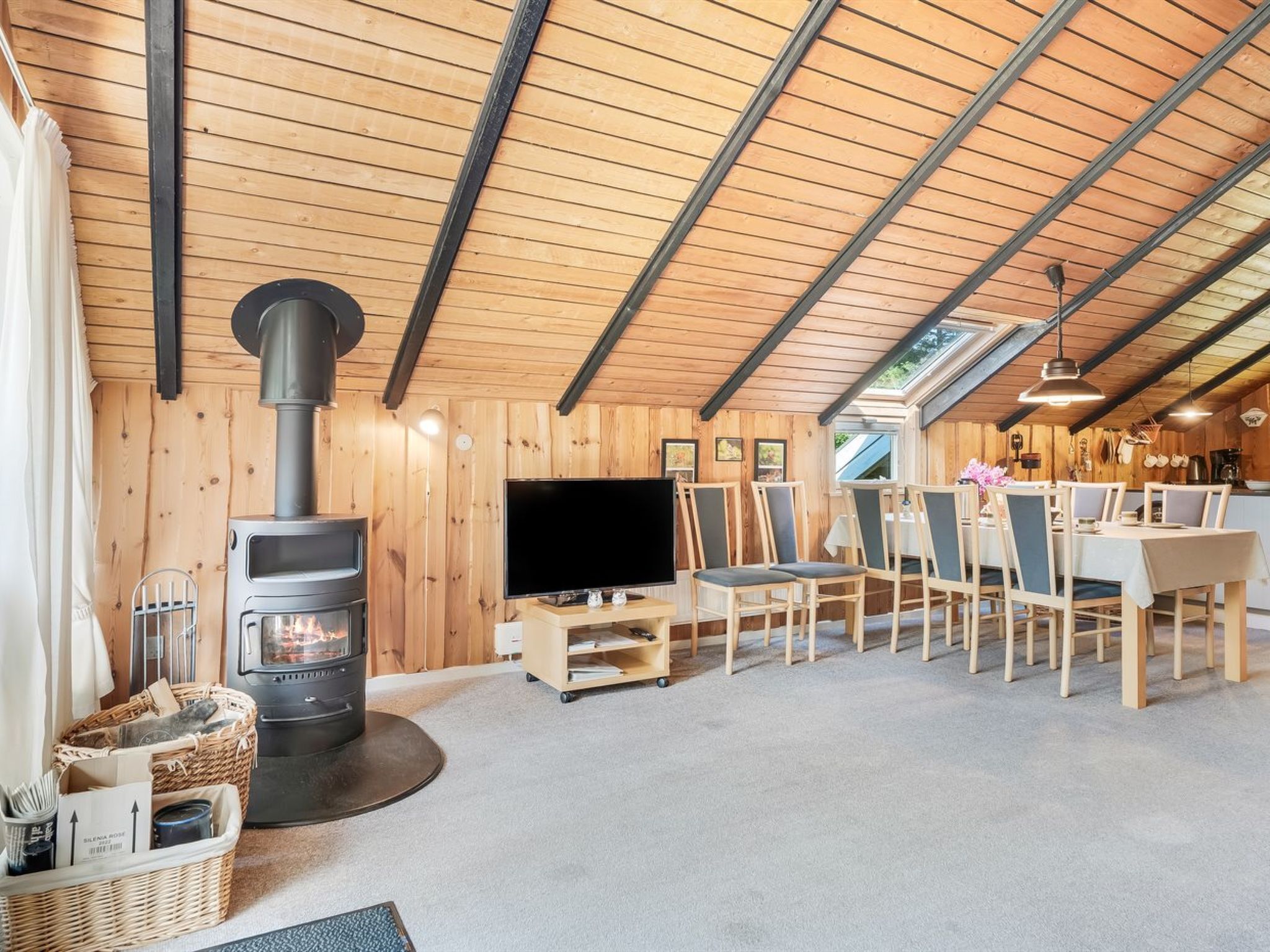 A cozy room with a wood stove, a TV, and a dining area with chairs and a table.