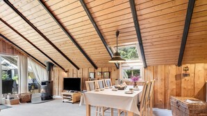 Un interior de madera con una mesa de comedor, sillas, un televisor y una chimenea.