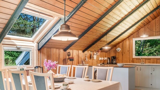 Un comedor con una mesa, sillas y vistas al exterior a través de tragaluces.