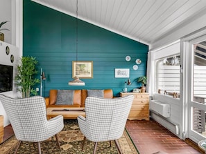 A room with teal walls, a sofa, two chairs, a small table, and a radiator.