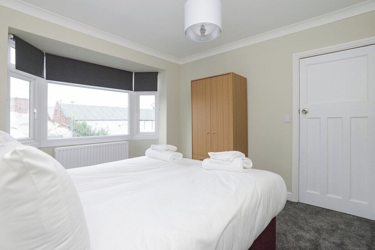 A hotel room with a bed, a wardrobe, a window with a view, and a door.