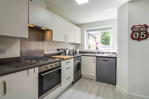 Cocina moderna con estufa a gas, horno, lavadora y lavavajillas.